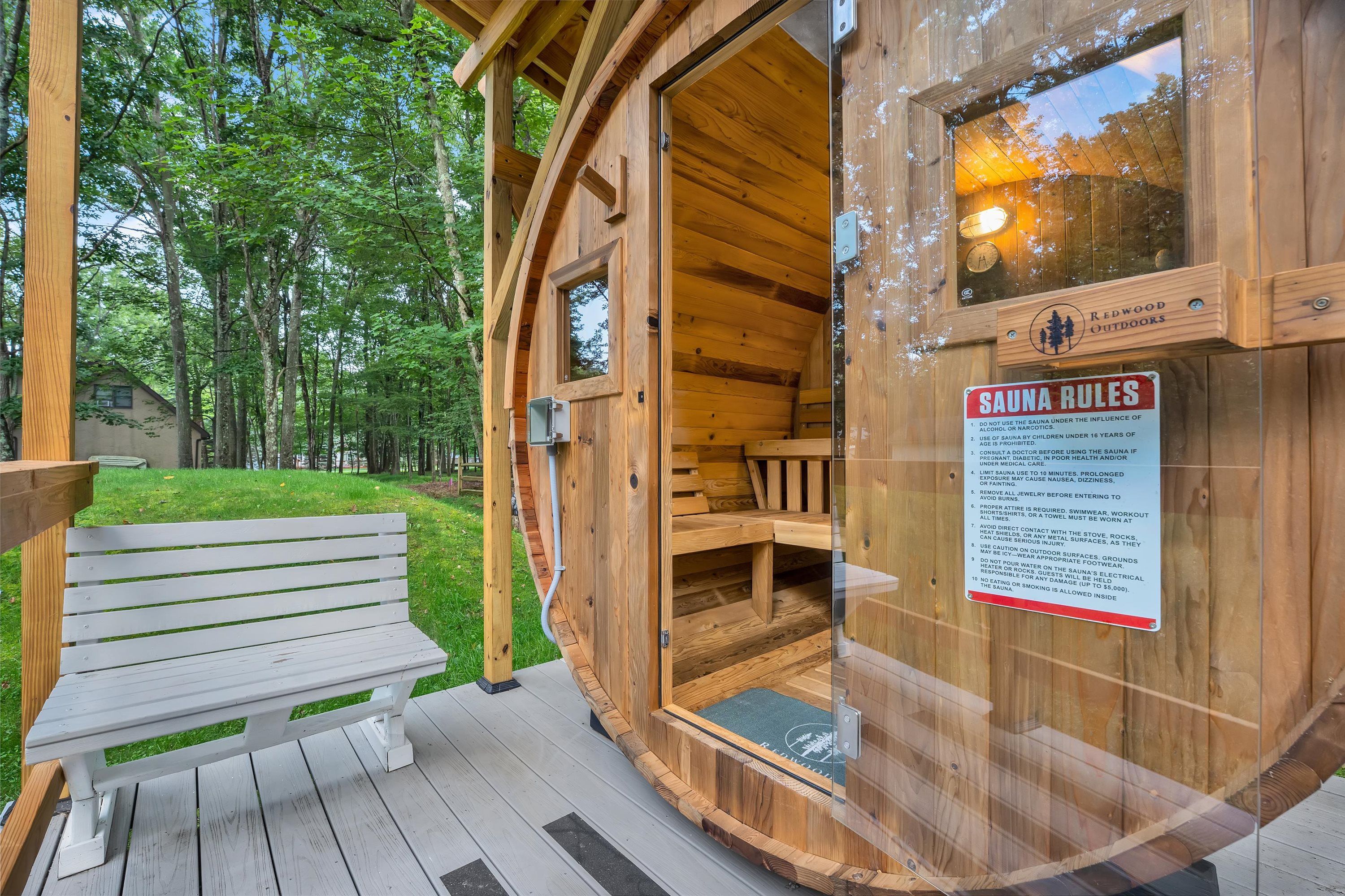 A wooden sauna with a sign listing sauna rules, a bench, and a glass door.