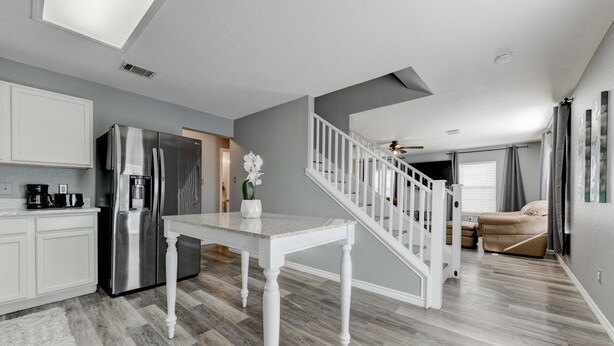 A modern kitchen with white cabinetry, a stainless steel refrigerator, and a dining table with a vase of flowers. - Georgetown Gem 💎 (Georgetown)