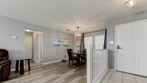 A spacious dining area with a wooden table and chairs, a white railing, and a door leading to another room. - Georgetown Gem 💎 (Georgetown)
