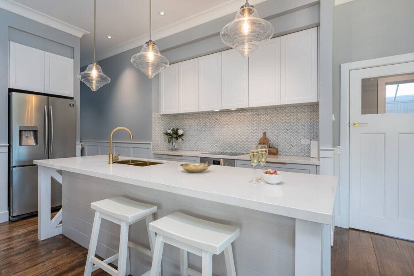 A modern kitchen with a central island, white cabinetry, and pendant lighting.