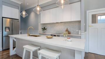 A modern kitchen with a central island, white cabinetry, and pendant lighting.