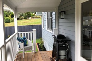 A porch with a white chair and a grill.
