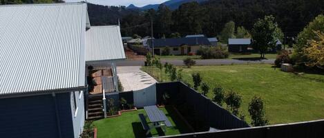 Un quartiere residenziale con una casa dotata di tetto in metallo a falda, un giardino sul retro con prato e un tavolo da picnic.