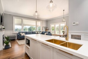 A modern kitchen with a large island, white cabinetry, and gold fixtures. - Luxury Villa With Gorgeous Views, We Sleep 11 (Marysville)