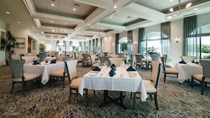 A spacious dining area with multiple tables set for service, large windows providing natural light, and a modern ceiling design. - Golf Membership Available! 2 BR/2BA, Pickleball, Pools, Near Gulf Beaches (Naples)
