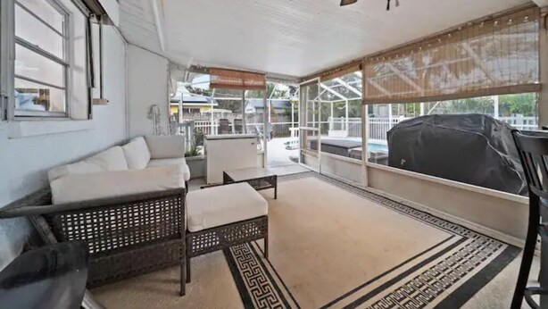 A covered patio area with a ceiling fan, wicker furniture, and a view of the outside.