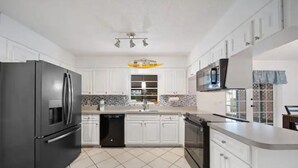 A modern kitchen with white cabinets, a black refrigerator, a microwave, and a dishwasher.