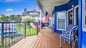 Una terraza de madera con paredes azules, una bandera y mobiliario para exteriores.