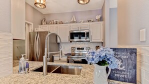 Una cocina con encimeras de granito, electrodomésticos de acero inoxidable y adornos en los armarios.