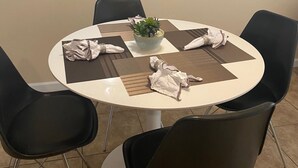 Een ronde tafel met een plantenaccessoire, omringd door zwarte stoelen.