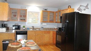 Una cocina con armarios de madera, un refrigerador negro y una ventana con persianas.