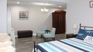 Un dormitorio con cama, dos sillas, un armario y un cuadro en la pared.