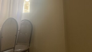 Habitación con ventilador de techo, televisor de pantalla plana en la pared y dos sillas cerca de una ventana con cortinas.