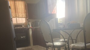Cocina con estufa, microondas y armarios. Hay sillas y una mesa de comedor.