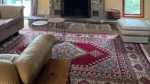 Una sala de estar con chimenea de piedra, un candelabro y un ventanal grande.