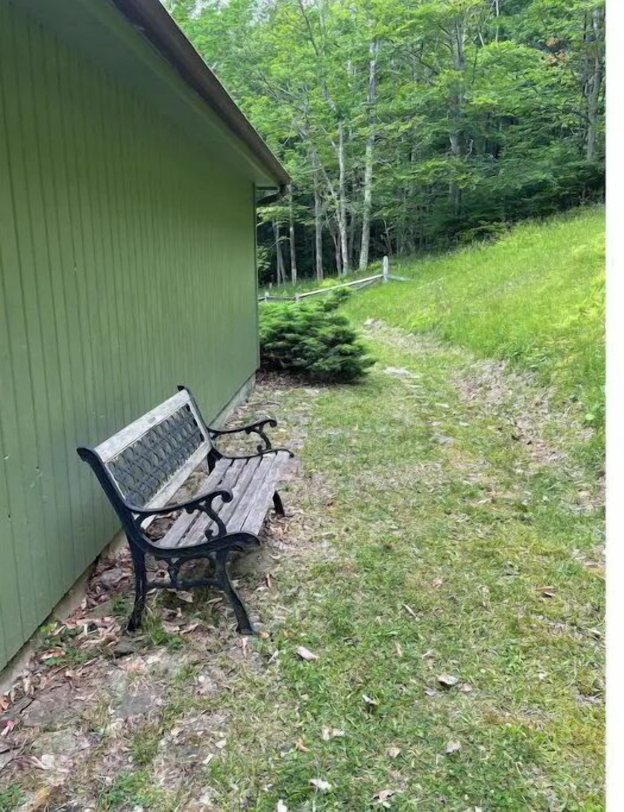 A green building with a bench outside.