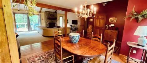 A dining area with a wooden table and chairs, a chandelier, and a patterned rug.