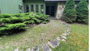 Una casa verde con cimientos de piedra, un camino de piedra y un césped bien cuidado.