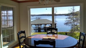 A dining area with a round table and chairs, a ceiling fan, and a view of a lake with a dock and trees. - Parkside Perch on Lake D'Arbonne - Backup Generator and New Boat Cradle (Bernice)