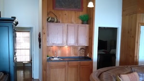 A kitchen with wooden cabinets, a sink, and a countertop. There is a dining area with a brown leather couch and a table. - Parkside Perch on Lake D'Arbonne - Backup Generator and New Boat Cradle (Bernice)