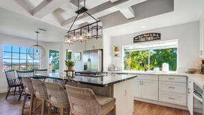 A modern kitchen with a large island, bar stools, and a view of greenery outside. - Custom 3,600sf Fallbrook Retreat: Wedding Guests•Family•Couples-Wine•Golf•Coast (Fallbrook)