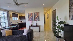 A modern living room with a sofa, a dining table, a TV, and a ceiling fan. - Marigold Apartment 4.  2 bedroom 2nd floor apartment with a great view. (Nadi)