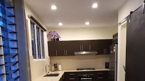 A modern kitchen with dark cabinets, a stainless steel refrigerator, and a built-in oven. - Marigold Apartment 4.  2 bedroom 2nd floor apartment with a great view. (Nadi)