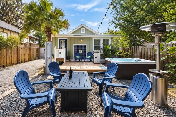 A backyard with a hot tub, outdoor seating, and a wooden deck.