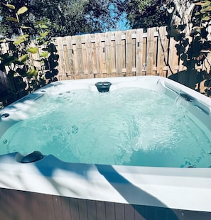 Relax in a hot tub with jets, surrounded by lush greenery.