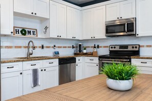 Une cuisine moderne avec des meubles blancs, un four à micro-ondes en acier inoxydable, un lave-vaisselle et une cuisinière.