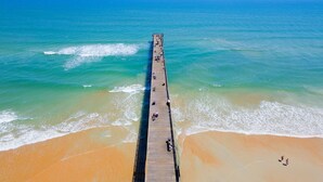 Un muelle largo que se adentra en el océano, con gente caminando a lo largo del mismo.