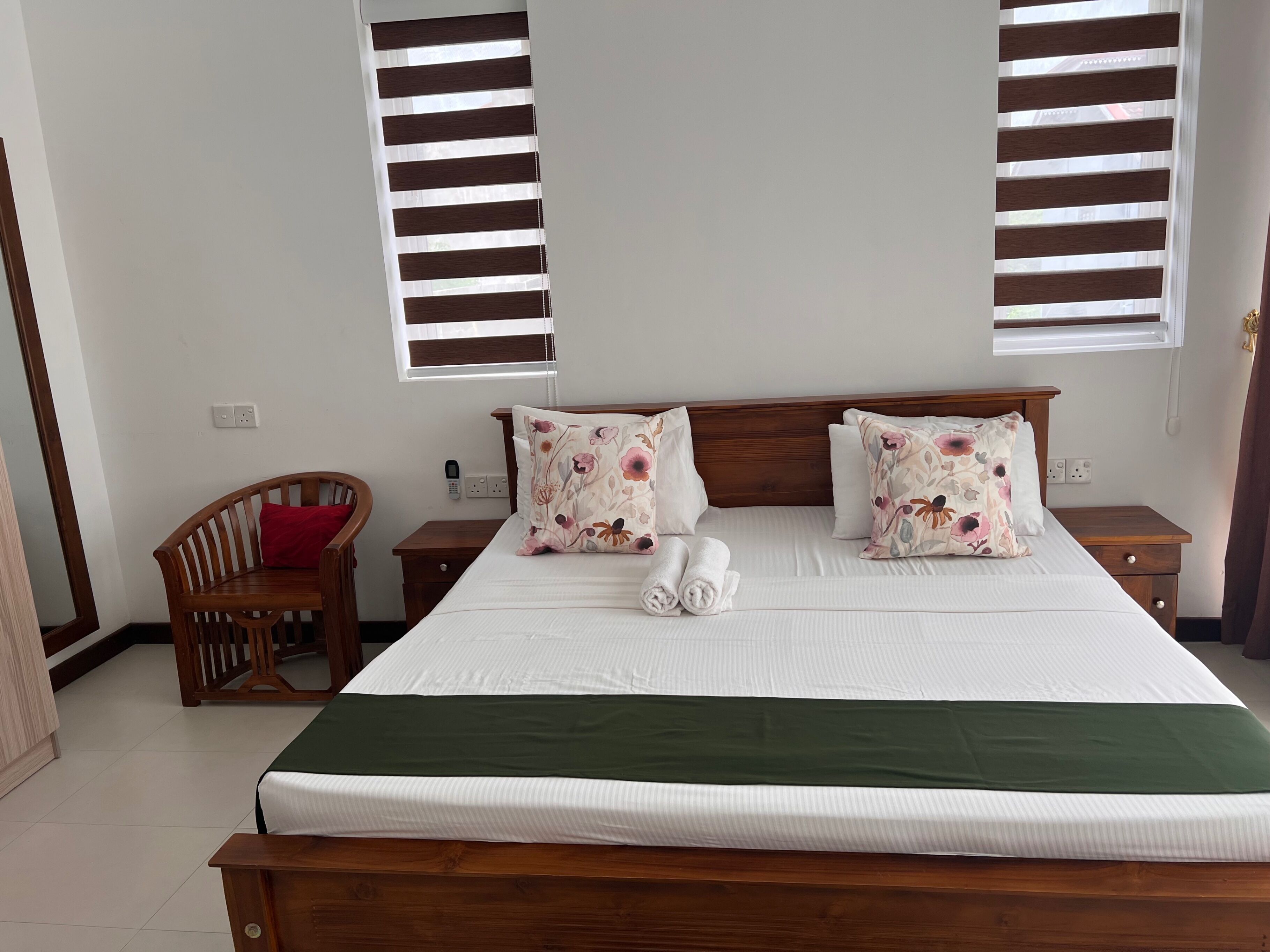 A neatly made bed with floral pillows, a wooden headboard, and a green bedspread.
