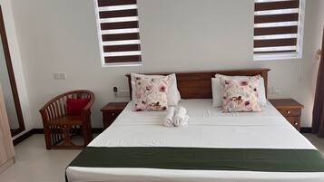 A neatly made bed with floral pillows, a wooden headboard, and a green bedspread.