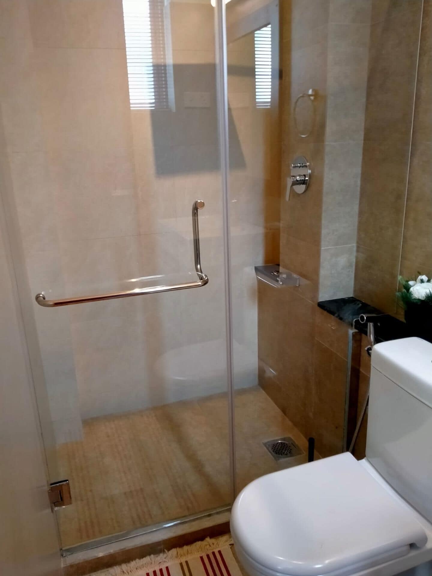 A bathroom with a glass-enclosed shower, a toilet, and a towel rack.
