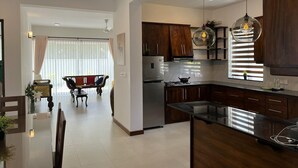 A modern kitchen with dark wooden cabinets, a stainless steel refrigerator, and a black countertop. - Silina Airport Residence in Katunayake (Seeduwa - Katunayake)