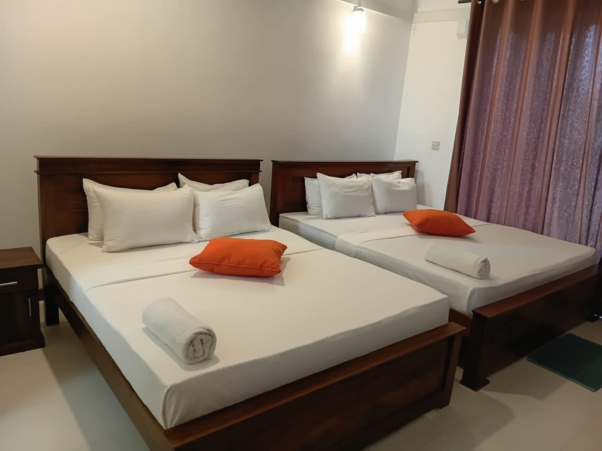 A hotel room with two beds, each with white linens and wooden headboards.