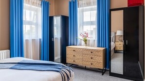 Ein Hotelzimmer mit einem Bett, einem Schminktisch, einem Spiegel und einem Fenster mit Vorhängen.