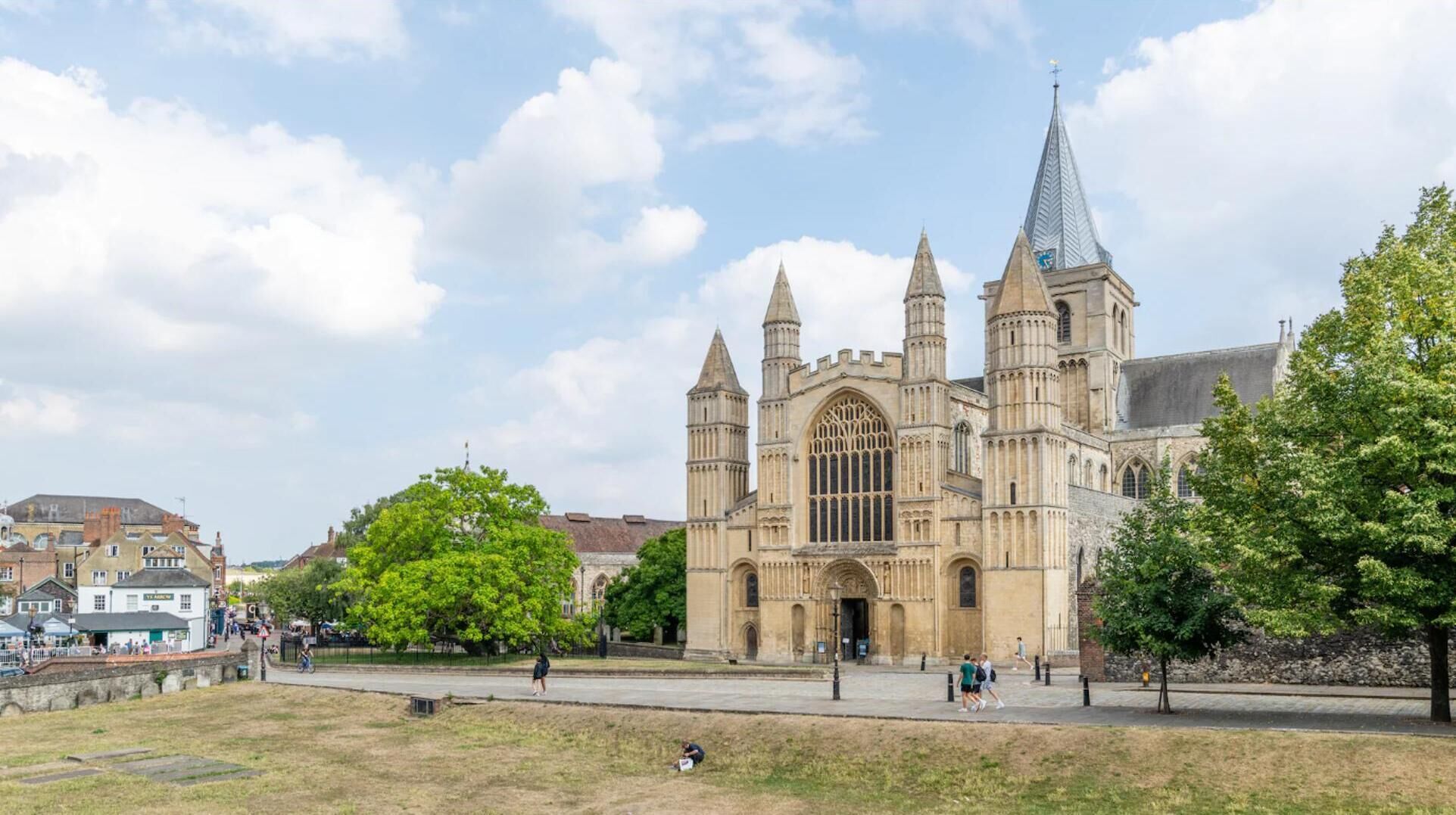 A historic cathedral with three spires, a large arched entrance, and a clock tower.