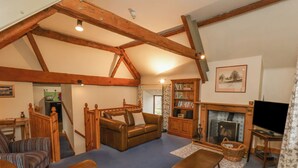 A cozy living room with a fireplace, leather sofas, a bookshelf, and a television. - Gateside (Pickering)
