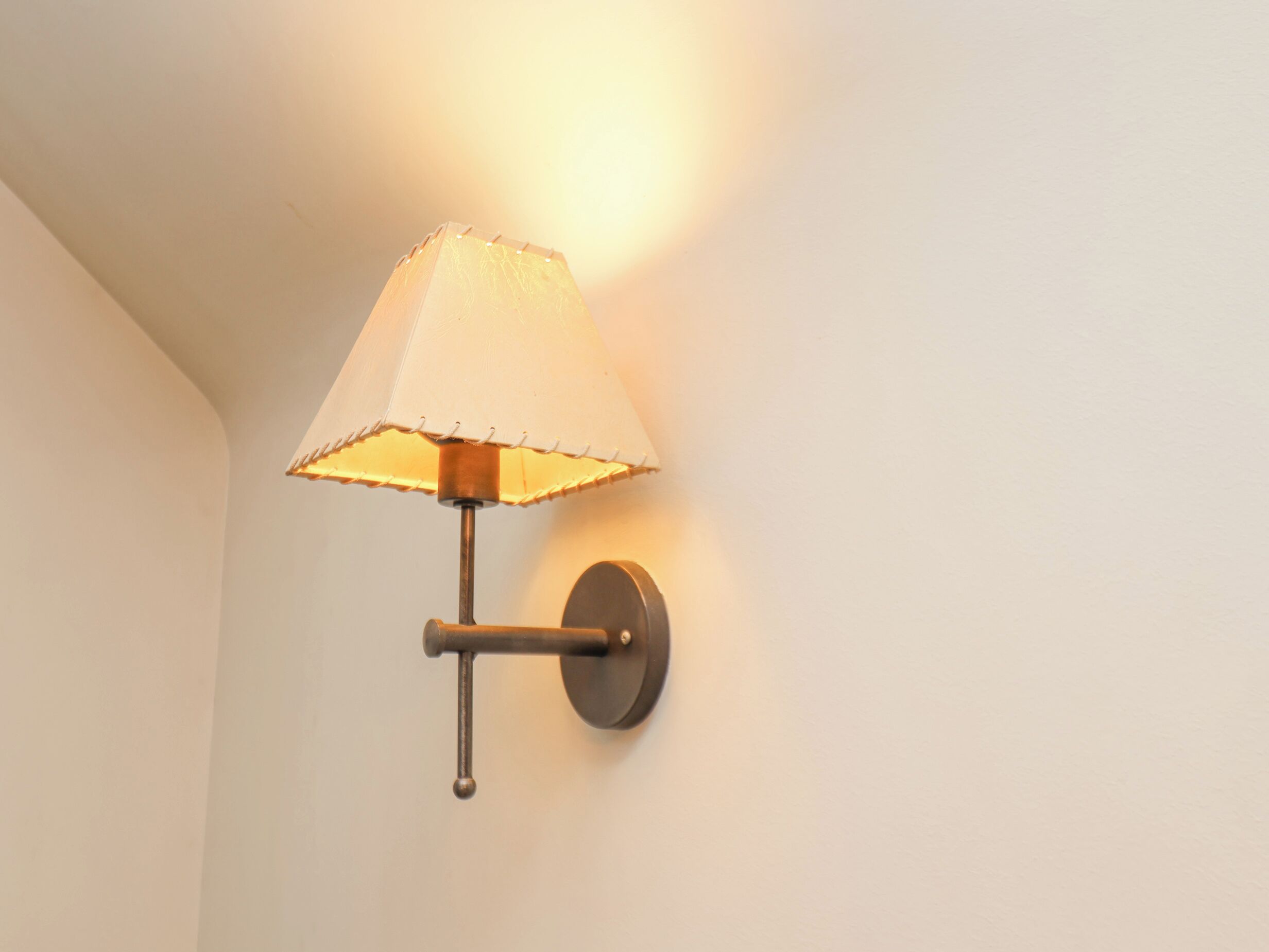Una lámpara de pared con pantalla de tela y base metálica.