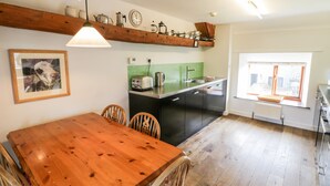 A kitchen with a wooden table, chairs, a green backsplash, and a window with a view. - Gateside (Pickering)