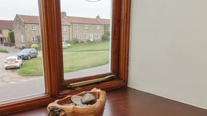A wooden bench with a carved design in a corner of a room with a large window. - Gateside (Pickering)