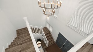 A staircase with wooden steps and white railings, leading to a landing with a door and a bench.