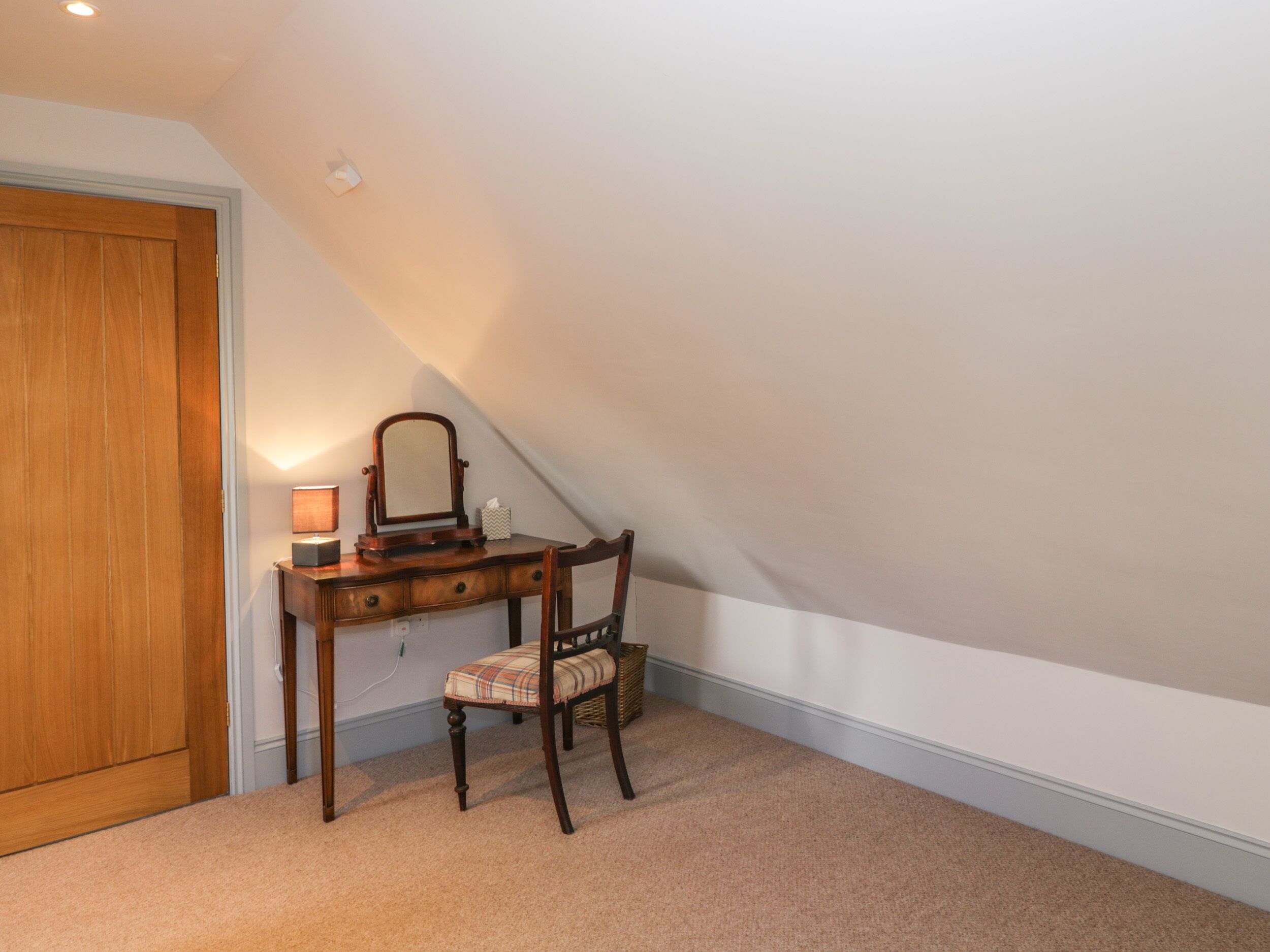 Une chambre à coucher avec un bureau en bois, une chaise et un miroir.