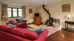 A cozy living room with a red sofa set, a fireplace, and a television. - Nine Acres Barn (Marlborough)