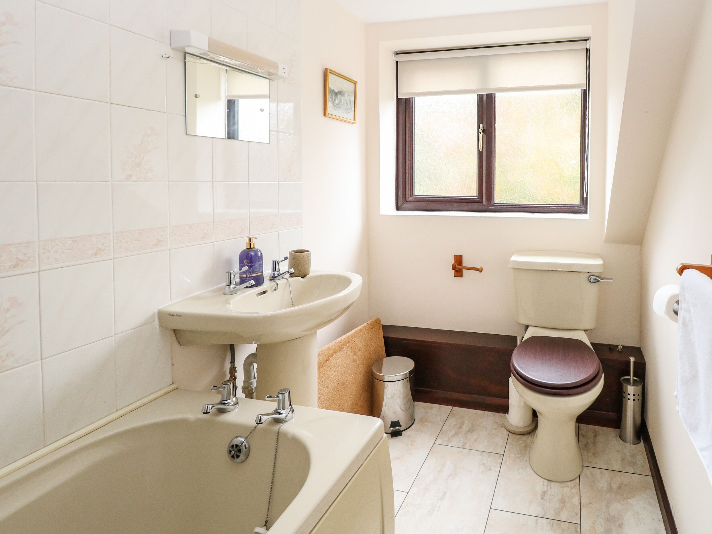 A bathroom with a bathtub, sink, toilet, and window.
