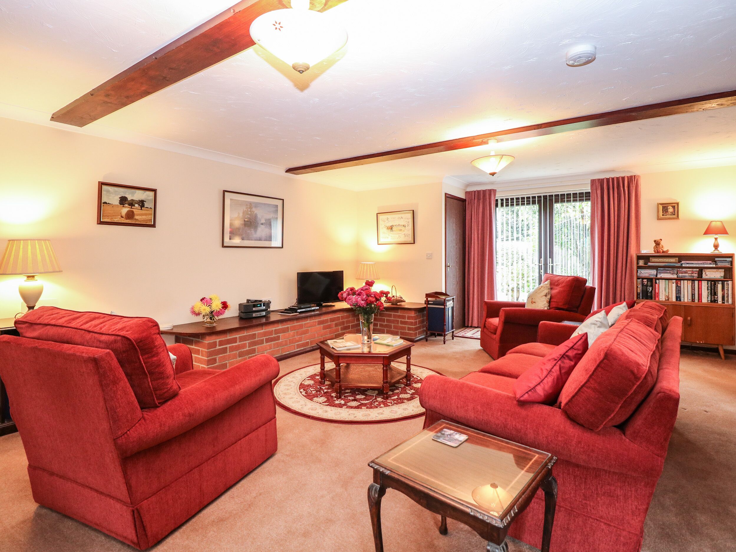 A living room with red sofas, a fireplace, a television, and a bookshelf.