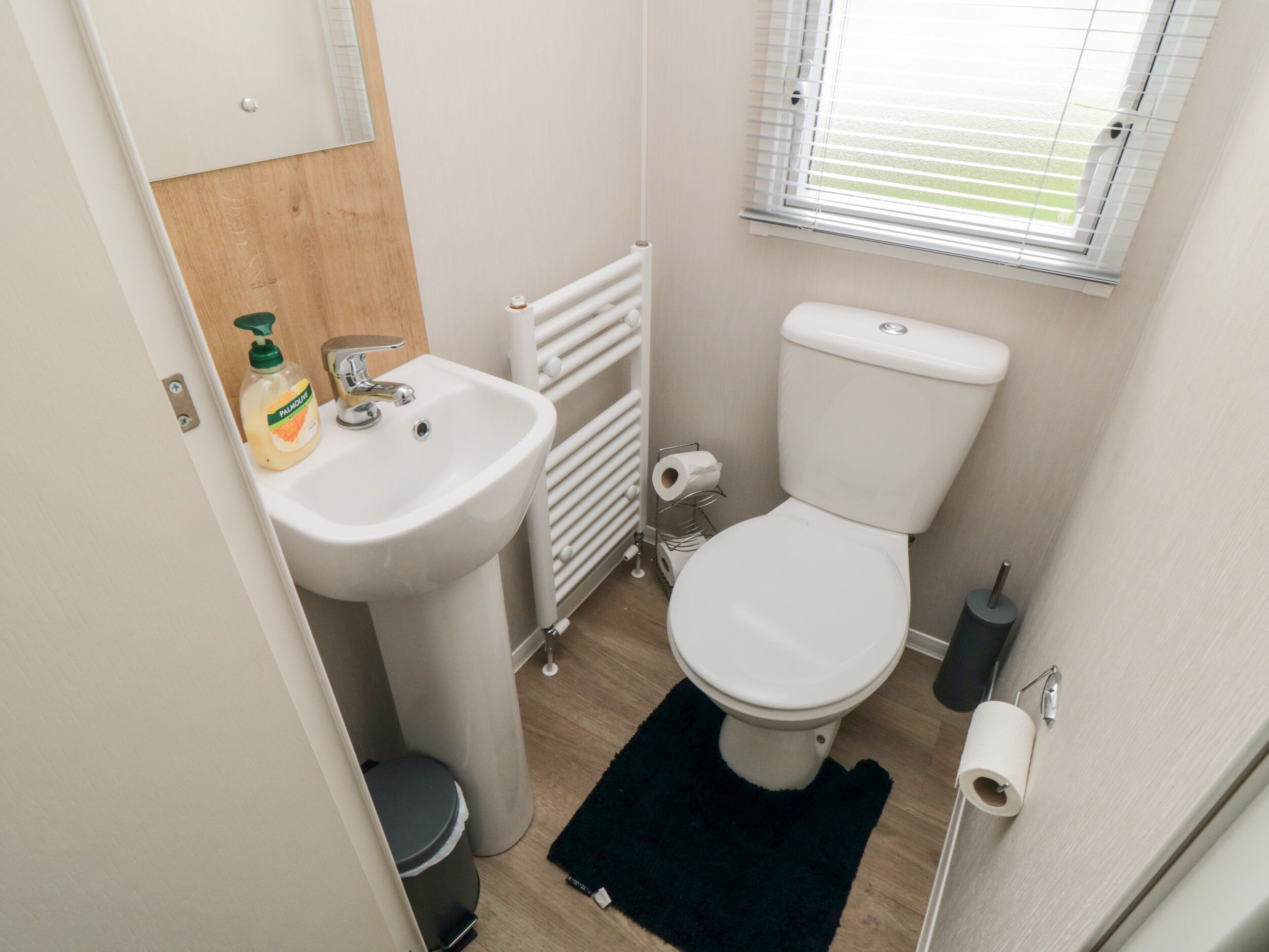 A compact bathroom with a white sink, toilet, and radiator.