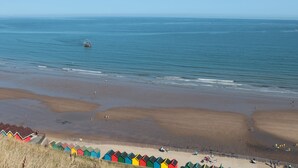 A beach with colorful beach huts and a boat in the water.