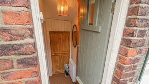 A narrow staircase leading to a wooden door, with a radiator and a wall-mounted light fixture.